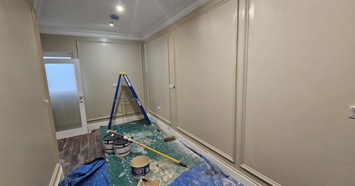Professional painter applying second coat of paint to interior wall in Monaghan